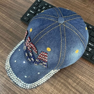 Detailed close-up of dark denim baseball cap with USA rhinestone design and shiny crystals