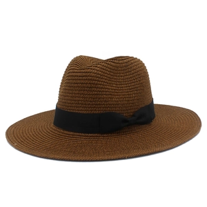 Detail of caramel straw fedora hat featuring a black ribbon bow and fine weave texture
