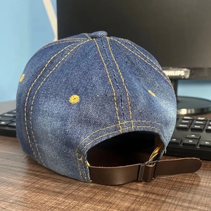 Denim baseball cap back view with yellow stitching and leather adjustable metal buckle