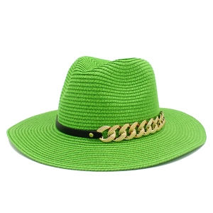 Détail du chapeau de paille vert avec chaîne dorée élégante et ruban noir décoratif