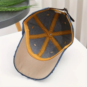 Detail of denim baseball cap interior featuring yellow stitching and leather strap
