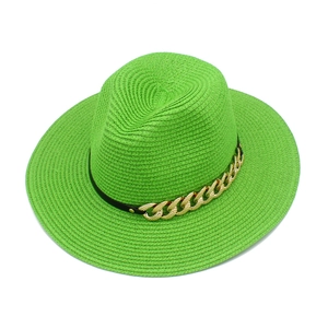 Détail d'un chapeau de paille vert vif avec ruban en cuir noir et chaîne dorée décorative