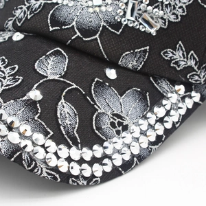 Dettaglio cappellino nero con ricami floreali in argento e strass scintillanti