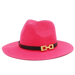 Dettaglio del cappello di paglia rosa con nastro nero e fibbia in metallo dorato