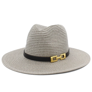 Dettaglio di cappello di paglia con fascia in pelle nera e fibbia dorata per stile estivo