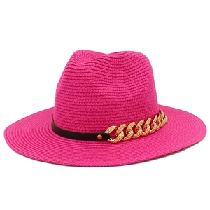 Détail du chapeau de paille rose avec ruban en cuir noir et chaîne dorée élégante
