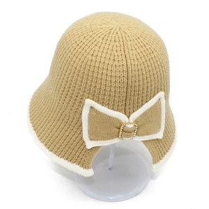 Detailed texture of camel knitted bucket hat with rhinestone bow and white trim edge