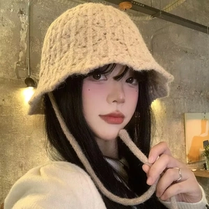 Close-up of beige knit bucket hat featuring thick texture and decorative strap ties