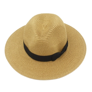 Detailed weave of natural straw beach hat featuring a black ribbon bow decoration