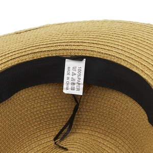 Detail view of the straw hat interior featuring 100% paper material and black sweatband