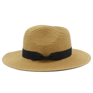 Close-up of hand-woven straw texture and wide black ribbon bow on summer beach sun hat