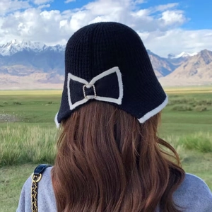 Outdoor back view of knitted bucket hat featuring a large bow and crystal buckle detail
