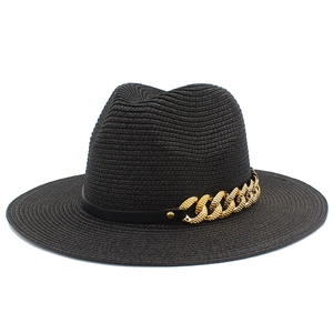 Détail du chapeau de paille noir avec une chaîne dorée élégante et un ruban en cuir chic