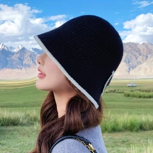 Detailed close-up of a black knitted bucket hat with white trim and ribbed texture