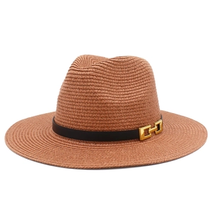 Dettaglio cappello di paglia marrone con fascia in pelle nera e fibbia in metallo dorato