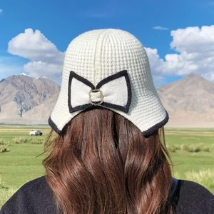Detail of white waffle knit bucket hat featuring a black bow and crystal buckle back