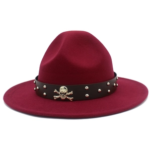Détail d'un chapeau fedora bordeaux avec emblème de crâne et bandeau clouté