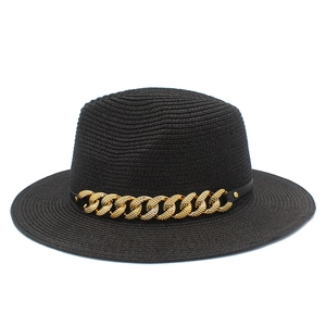 Détail du tressage de la paille avec chaîne dorée mate et ruban en cuir sur le chapeau