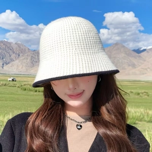 Close-up of cream knit bucket hat with black trim and elegant bow detail at back