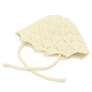 Detailed macro view of cream knitted bucket hat with hollow crochet patterns and long straps