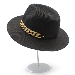 Détail d'un chapeau de paille noir classique avec chaîne dorée et ruban décoratif en cuir