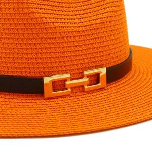 Dettaglio cappello di paglia arancione con fascia nera e fibbia a catena oro