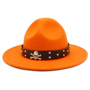Détail d'un chapeau en laine orange avec ruban en cuir noir et emblème de crâne