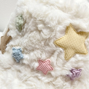Dettaglio ravvicinato del cappello a secchiello in ecopelliccia bianca con stelle colorate