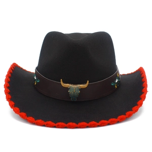 Detail of western cowboy hat with bull skull metal accessory and red stitched brim