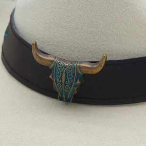 Detail of western hatband with vintage bull skull emblem and turquoise metal accents