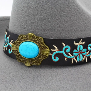 Detail of gray wool felt fedora with turquoise embroidery and brass buckle on leather band