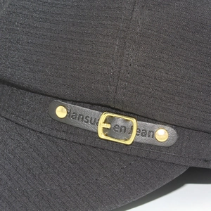 Detailed macro view of black octagonal hat featuring leather strap and gold buckle hardware