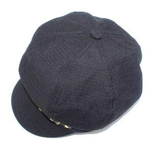 Detail of a black newsboy cap featuring textured fabric and decorative gold metal buttons