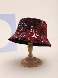 Detail of bohemian bucket hat with vintage red and black print on a wooden stand