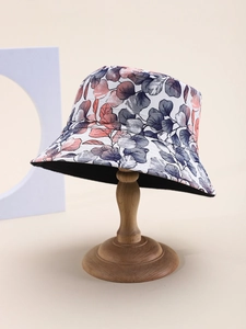 Detailed texture of cotton bucket hat with pink leaf print on wooden stand