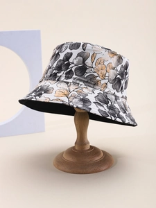 Detail of leaf print bucket hat showing grey and orange pattern on a wooden stand