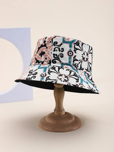 Detail of baroque print bucket hat on wooden stand showing canvas texture and art style