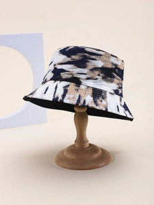 Close-up of tie-dye bucket hat with navy ink pattern on a wooden stand