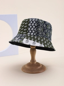 Détail d'un bob en patchwork avec des motifs floraux verts et bleu marine sur un support