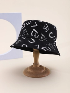 Détail d'un chapeau bob en coton noir avec graffiti de lettres et cœurs sur support bois