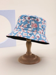 Dettaglio cappello alla pescatora floreale in tessuto azzurro con fiori rosa su legno