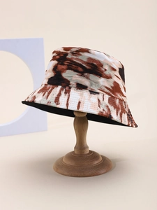 Close-up of double-sided tie-dye bucket hat with brown abstract patterns on a wooden stand