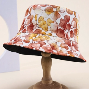 Stylish bucket hat with autumn leaf print on wooden stand for outdoor sun protection