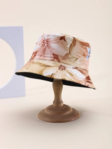 Detail view of floral print bucket hat on vintage wooden stand in warm orange tones