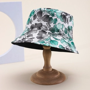 Green leaf print bucket hat for women on wooden stand for outdoor sun protection