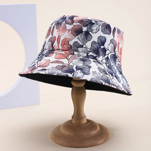 Reversible bucket hat with pink and grey leaf print and black lining on wooden stand