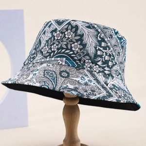 Blue-grey floral print bucket hat with paisley pattern on wooden stand for sun protection