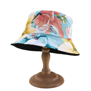 Fashionable floral bucket hat for women with tropical print and black lining on wooden stand