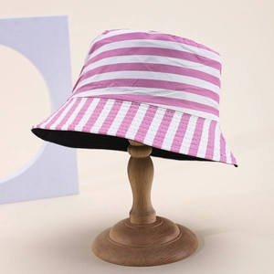 Pink and white striped bucket hat on a wooden stand with a minimalist studio background