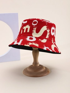 Detailed shot of red graffiti bucket hat with white letter prints on wood display stand
